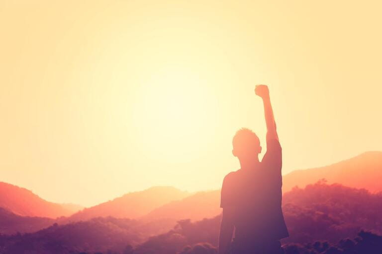 Copy space of man hand raising on top of mountain and sunset sky abstract background. Freedom travel adventure and business victory concept. Vintage tone filter effect color style.