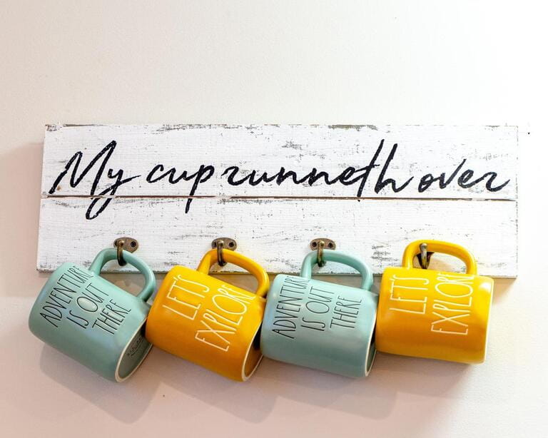 Decorative display of coffee mugs with quote, "My cup runneth over"